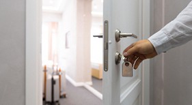 Person taking a key out of a partially open door.